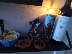 An altar with clay bowls, a statue, a candle and a bottle of wine