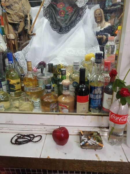 Various objects on a shelf in front of some bottles