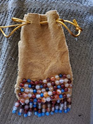 a brown suede pouch with rows of beads sewn along the bottom